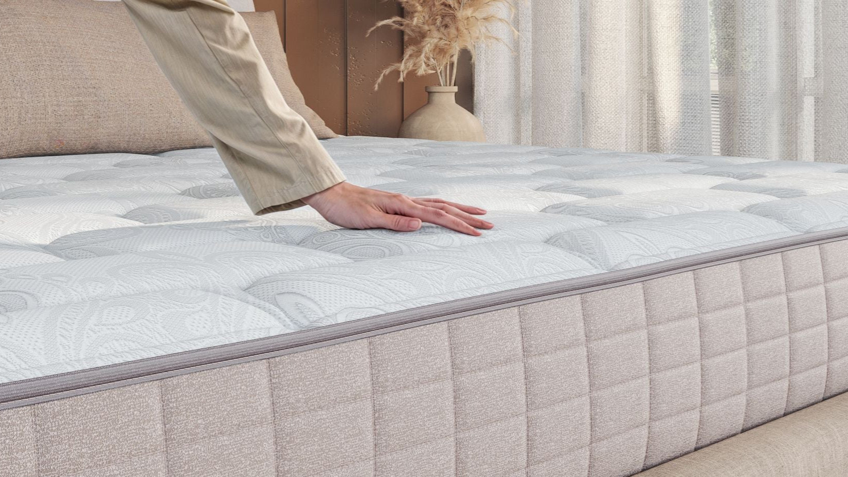 A lady touching the top layer of the mattress. 