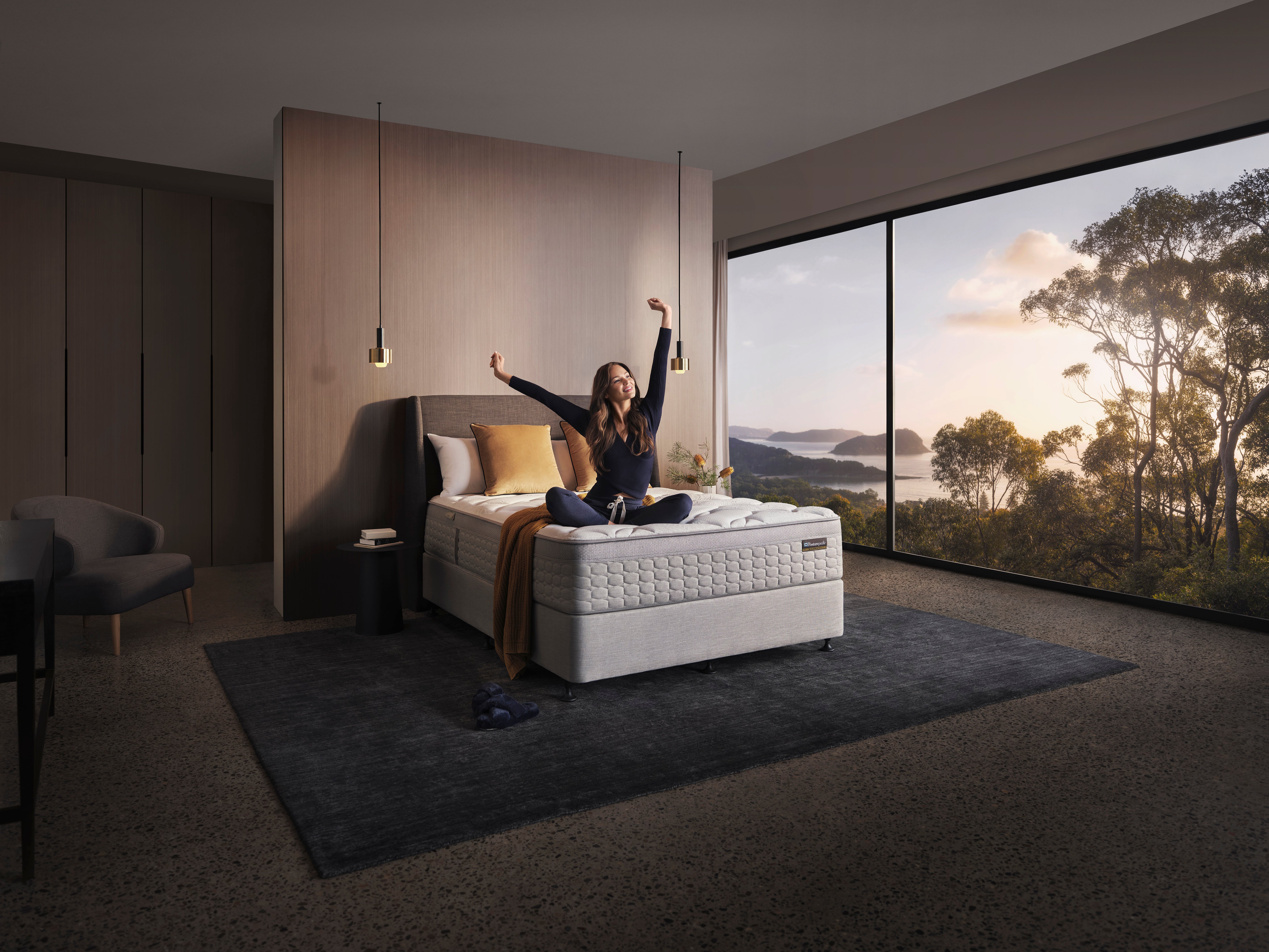 Woman stretching on Sealy mattress with scenic sunrise view